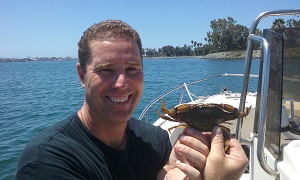 Kevin Hovel on boat holding a swimming crab