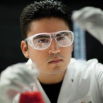 Headshot of Genaro Hernandez in lab with flask.